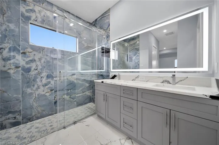 Bathroom with a marble finish shower, marble finish floors, double vanity, and recessed lighting