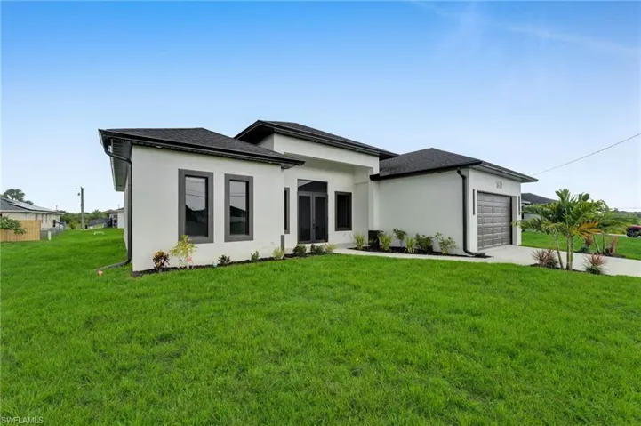 View of front of house featuring an attached garage, a front lawn, concrete driveway, and stucco siding