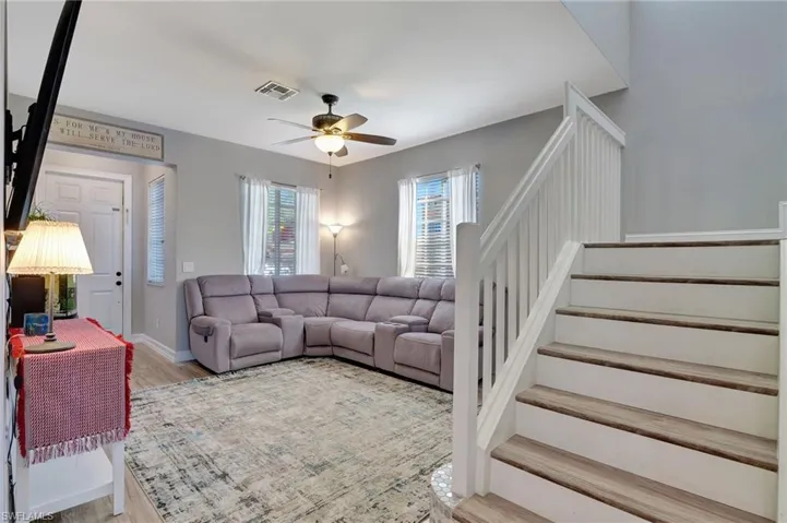Living room featuring high end neutral laminate flooring and ceiling fan