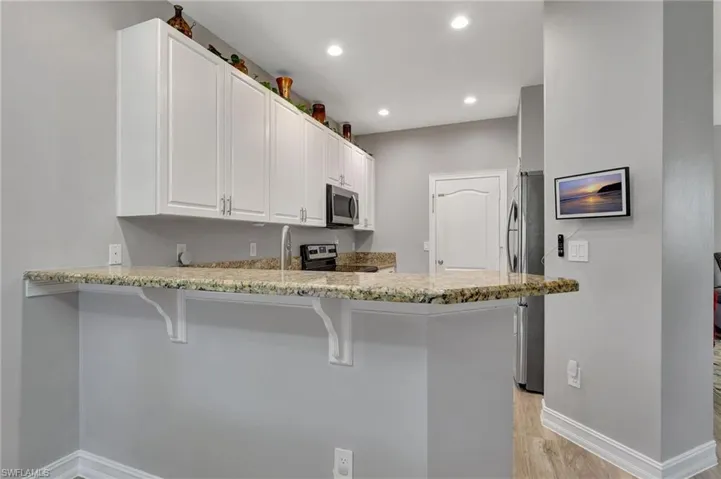 Kitchen featuring kitchen peninsula, a kitchen bar, stainless steel appliances and white cabinetry