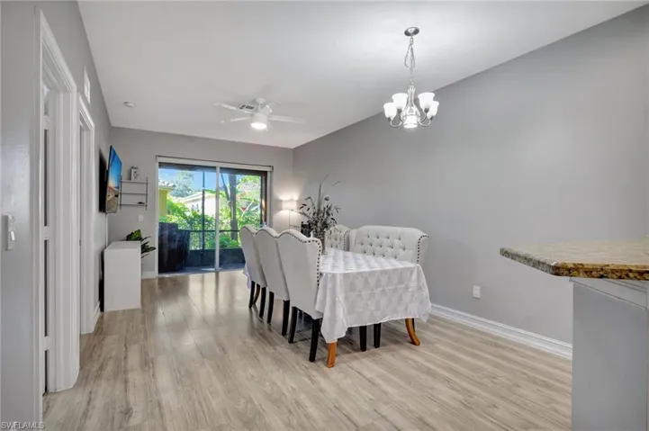 Dining space with ceiling fan with notable chandelier and light hardwood / wood-style floors