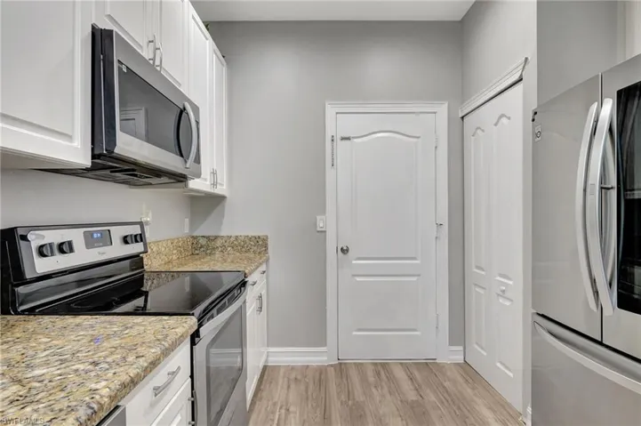 Kitchen with granite countertops, white cabinets, and appliances with stainless steel finishes
