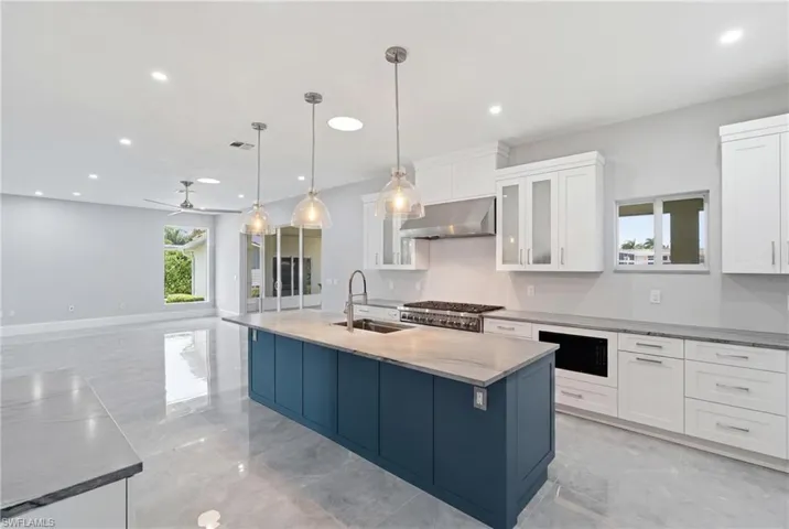 Spacious kitchen featuring a large island with a sink and pendant lighting