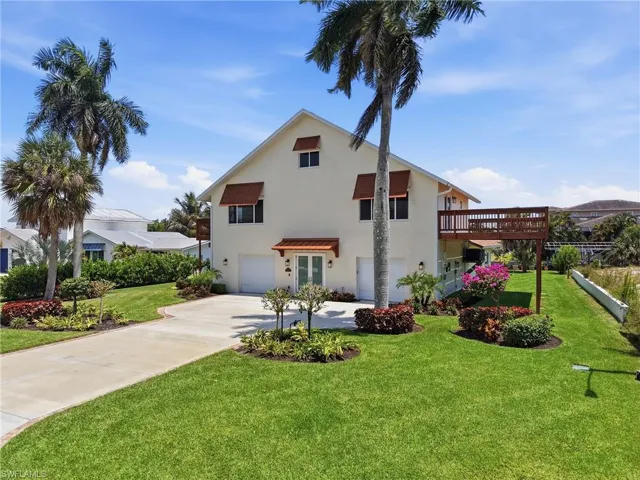 Contemporary multi-level residence featuring a large elevated deck, dual garage doors, and a concrete driveway