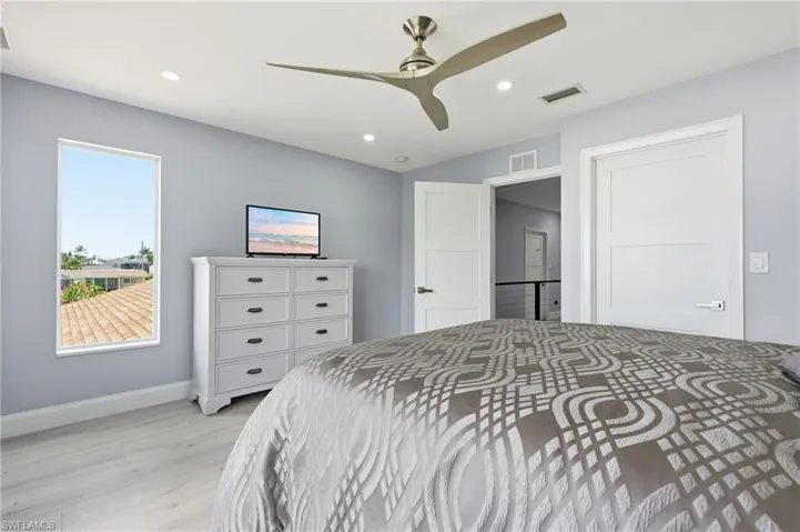 Recessed lighting, a modern ceiling fan, and light wood-finish flooring characterize this room