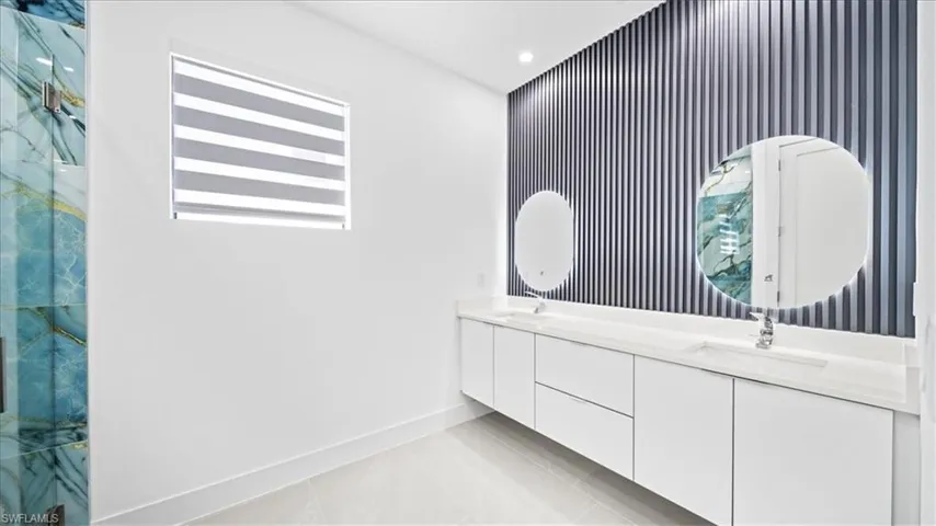 Bathroom with double vanity, an accent wall, recessed lighting, light tile patterned floors, and wallpapered walls