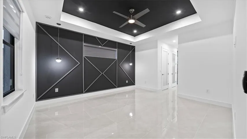 Empty room with a raised ceiling, recessed lighting, and ceiling fan