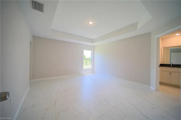 Empty room featuring a tray ceiling and light tile floors