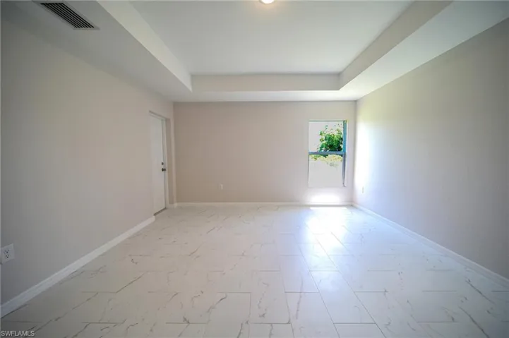 Tiled spare room with a raised ceiling