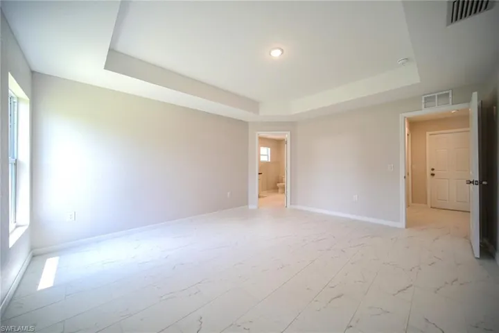 Tiled spare room with a tray ceiling
