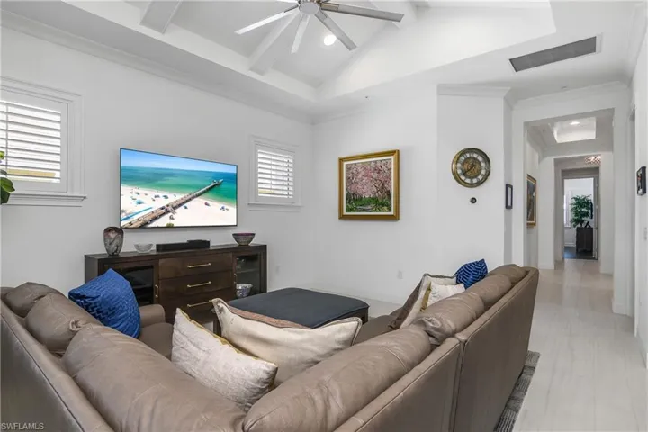 Living room with beam ceiling, ceiling fan, and crown molding. Modern living space that merges nicely with the Kitchen and dining areas. Plantation shutters on windows.