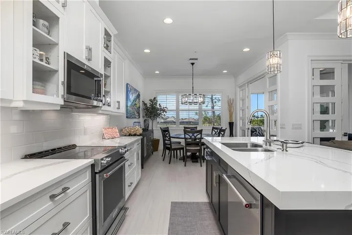 Kitchen with appliances with stainless steel finishes, a kitchen island, decorative light fixtures, and white cabinets. Note the thick 3" mitered Edge on the Island Quartz.