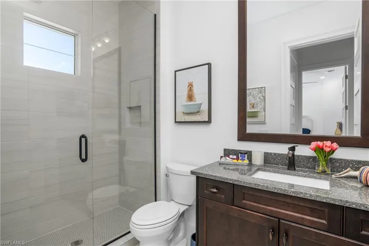 Guest Bathroom featuring vanity, a walk-in shower, framed mirror.