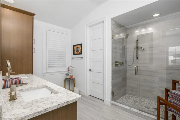 Bathroom featuring lofted ceiling, vanity, and an enclosed shower