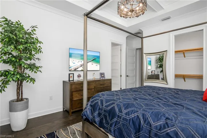 Master Bedroom featuring crown molding, dark wood-flooring, and an inviting chandelier. Walk-in Closet.