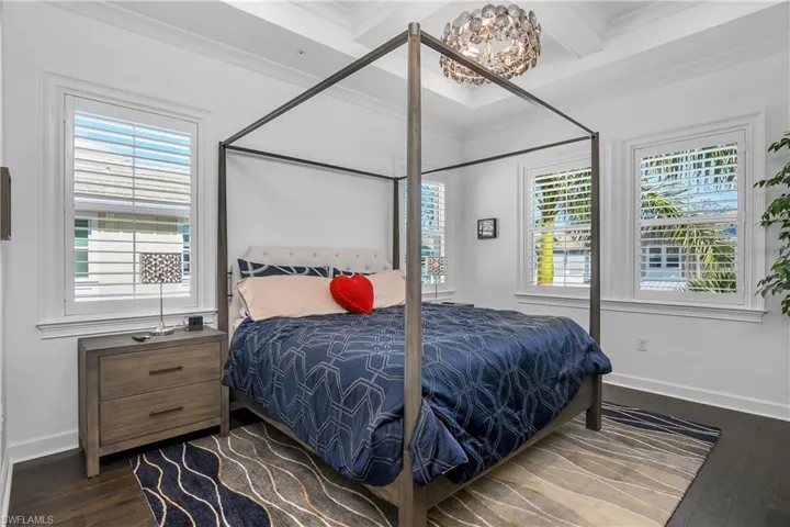 Master Bedroom featuring beam ceiling, dark hardwood / wood-style flooring, an inviting chandelier, and crown molding. Plantation Shutters on every window.