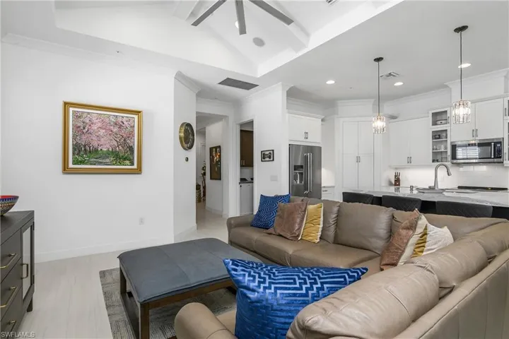 Living room with vaulted ceiling with beams, ceiling fan, light hardwood / wood-style floors, views of the Kitchen.