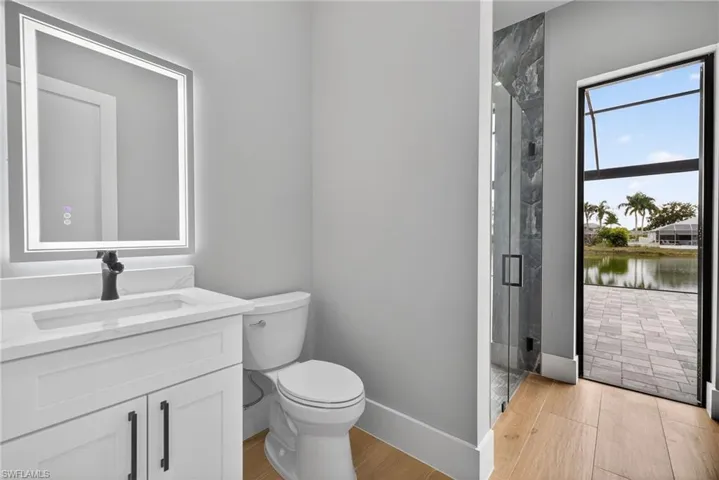Full bath with vanity, a marble finish shower, light wood-style floors, and a water view
