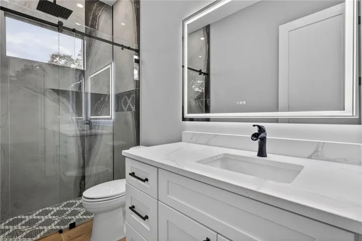 Full bathroom featuring a marble finish shower and vanity