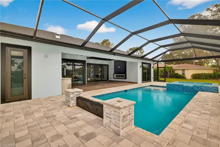 View of swimming pool featuring a sunroom, a pool with connected hot tub, a lanai, and a patio