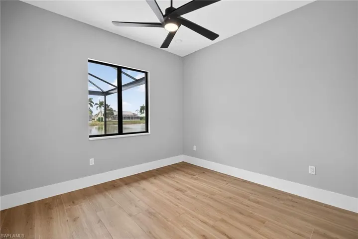 Empty room featuring a water view, light wood finished floors, and a ceiling fan