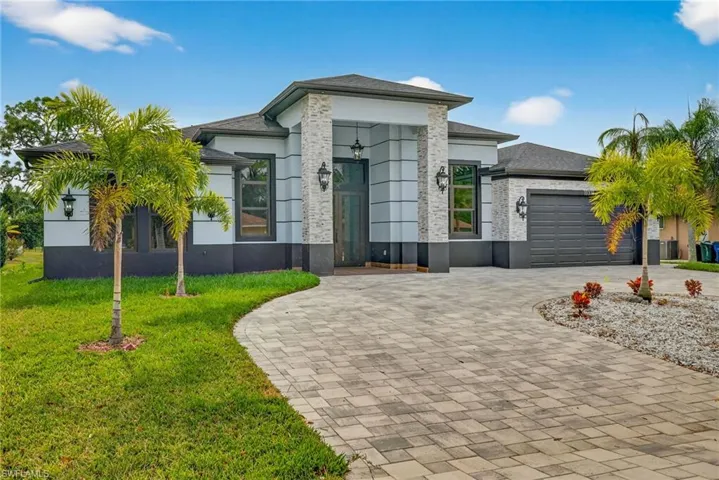 View of front facade featuring decorative driveway, a front lawn, a garage, and stucco siding