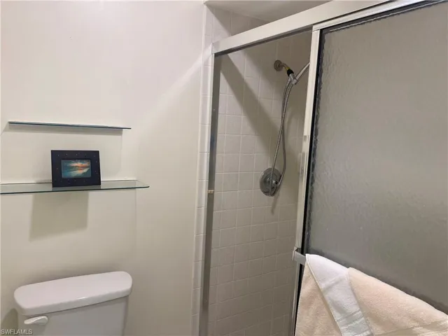 Bathroom featuring a shower with shower door and toilet