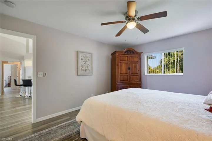 Bedroom featuring dark wood-type flooring, a ceiling fan, and freestanding refrigerator