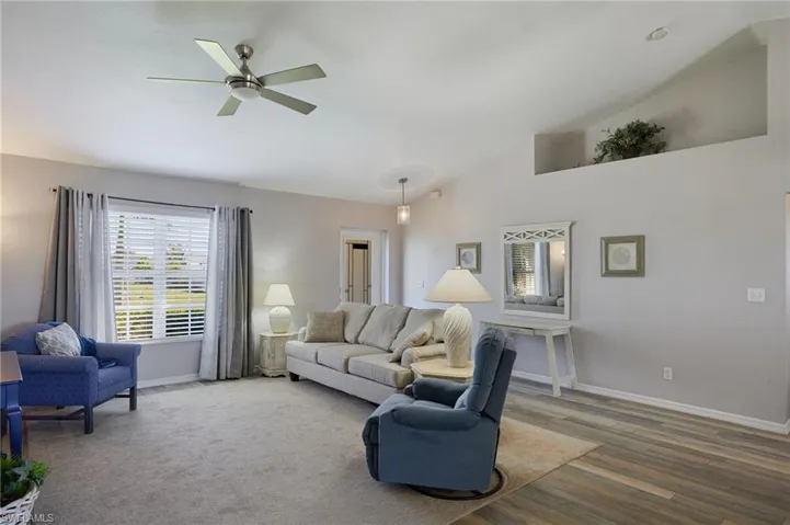 Living area with a ceiling fan, wood finished floors, and high vaulted ceiling
