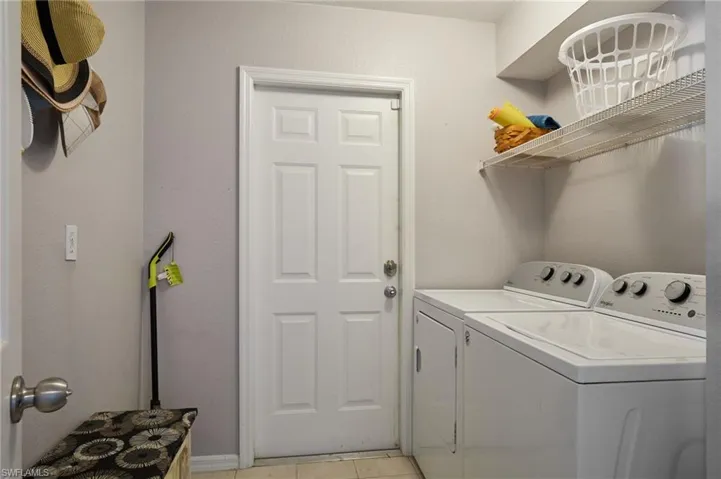 Laundry room featuring washing machine and clothes dryer and light tile patterned flooring