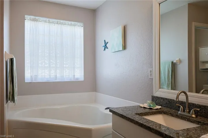 Full bathroom with vanity, a garden tub, and a textured wall