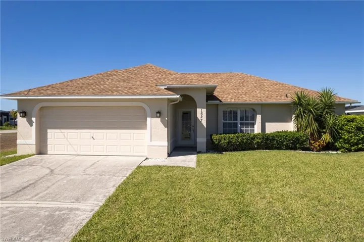 Ranch-style home with stucco siding, a shingled roof, driveway, a front lawn, and an attached garage