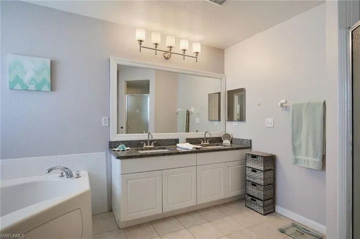 Bathroom with a stall shower, double vanity, a bath, light tile patterned floors, and a textured ceiling