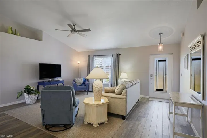 Living room with wood finished floors, a ceiling fan, and vaulted ceiling