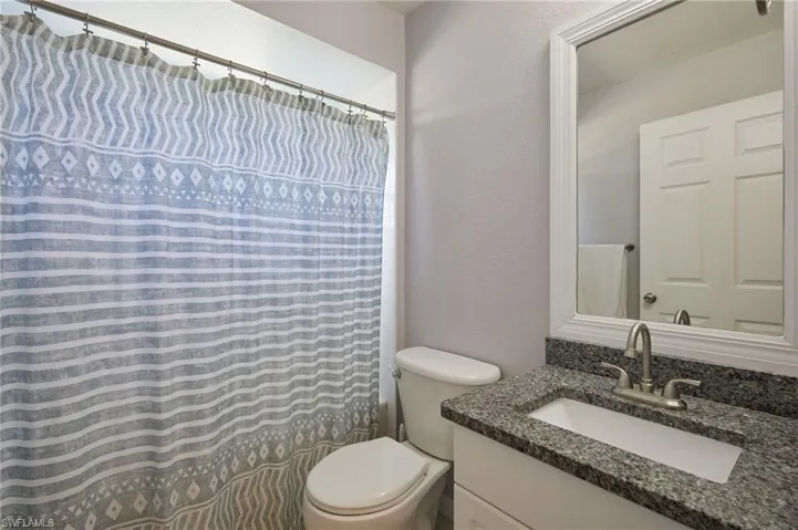 Bathroom with a textured wall, a shower with shower curtain, and vanity