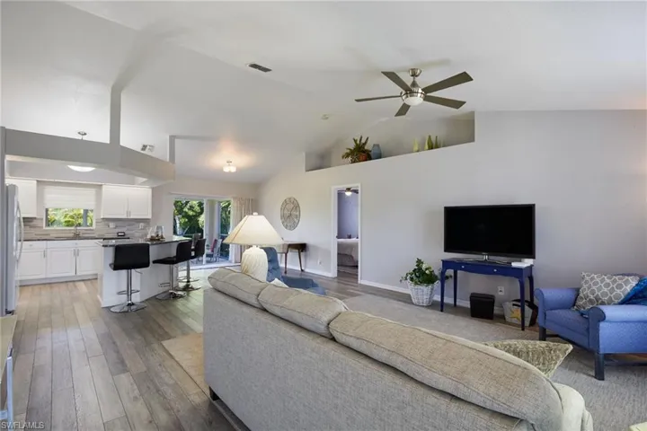 Living area with ceiling fan, high vaulted ceiling, light wood-type flooring, and french doors