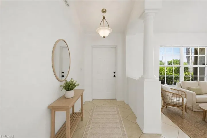 Bright foyer featuring a paneled entry door, overhead light fixture, and tile flooring with a decorative runner