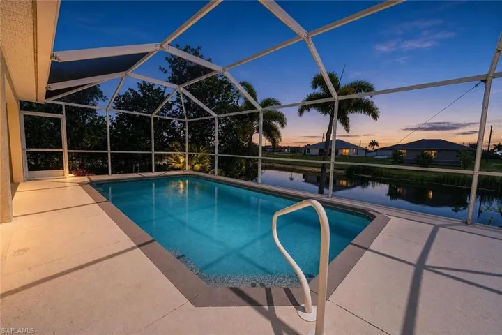 Screened-in swimming pool with a perimeter deck, featuring a handrail for access