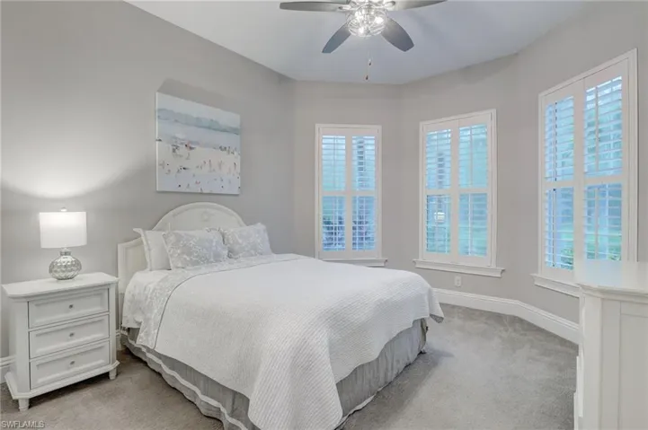 Bedroom with ceiling fan and light colored carpet