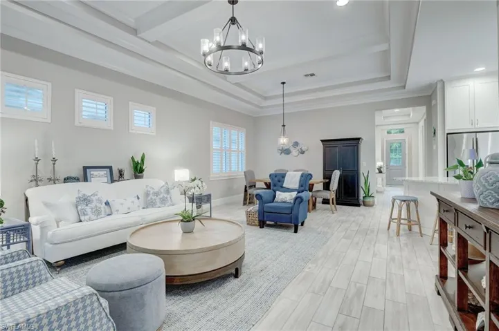 Living room featuring a tray ceiling, crown molding, light wood-type flooring, and an inviting chandelier