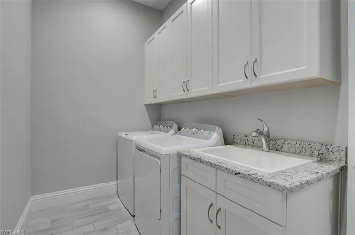 Laundry area featuring washer and dryer, cabinets, sink, and light wood-type flooring