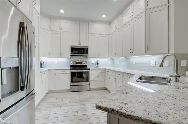 Kitchen with white cabinetry, backsplash, and stainless steel appliances