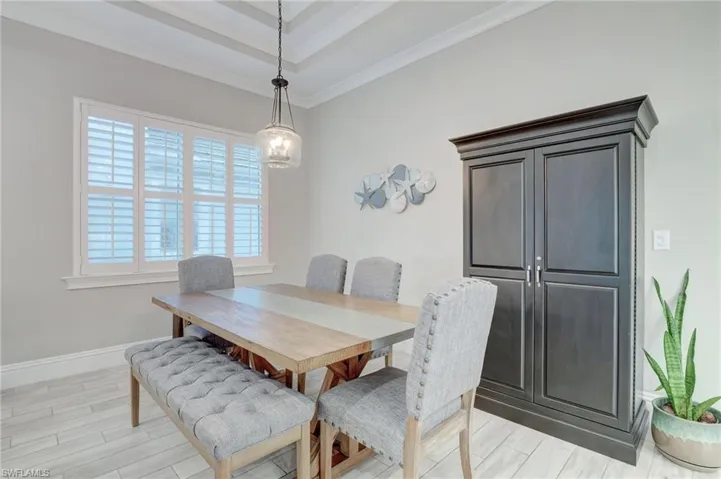 Dining area featuring a healthy amount of sunlight, ornamental molding, light hardwood / wood-style floors, and a raised ceiling