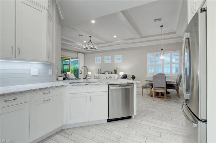 Kitchen with stainless steel appliances, white cabinets, backsplash, and pendant lighting