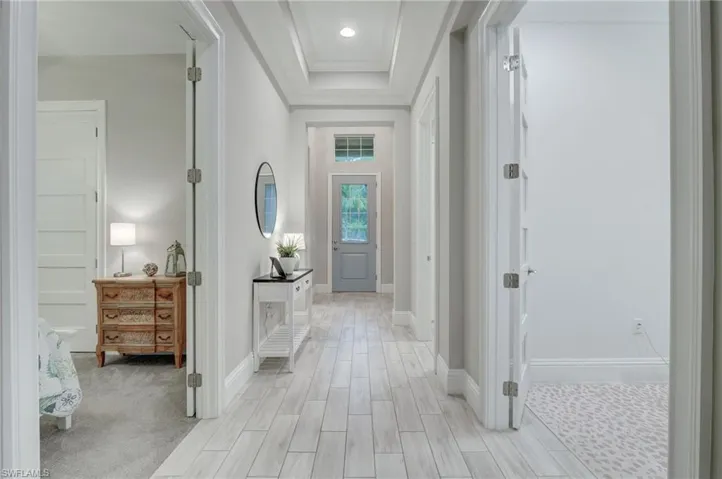 Hallway with light carpet and a raised ceiling