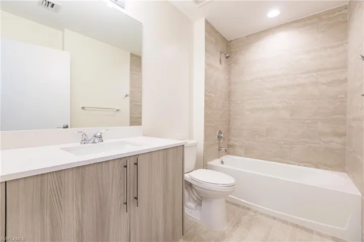 Full bathroom featuring tile flooring, vanity, toilet, and tiled shower / bath combo