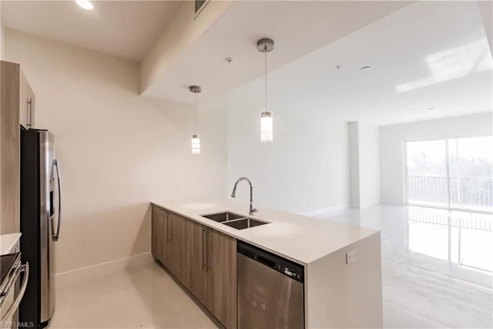 Kitchen featuring hanging light fixtures, stainless steel appliances, sink, and light tile floors