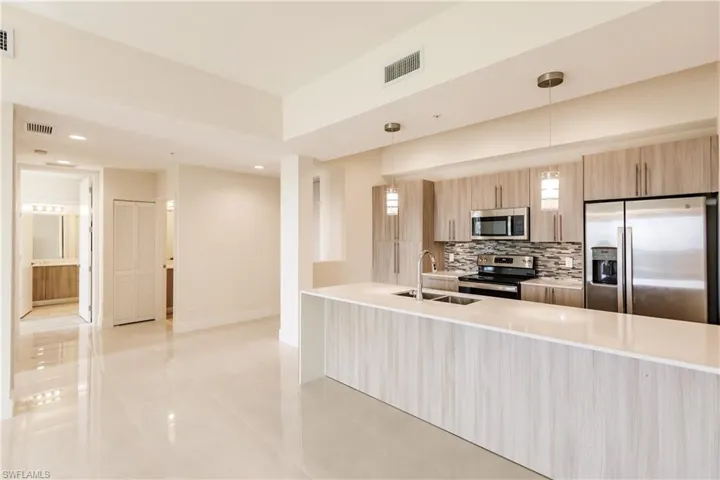 Kitchen featuring appliances with stainless steel finishes, backsplash, pendant lighting, sink, and light brown cabinets