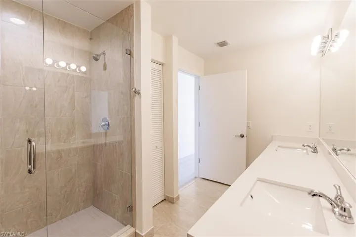 Primary bathroom with double vanity, and enclosed shower, and tile floors