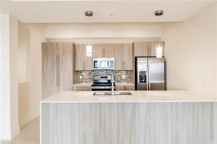 Kitchen featuring stainless steel appliances, backsplash, pendant lighting, sink, and light tile floors